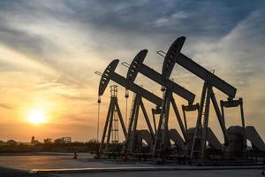 Oil rig or Oil field site, in the morning or evening, oil pumps are running, The oil pump and the beautiful sunset or sunrise of pumping unit. photo