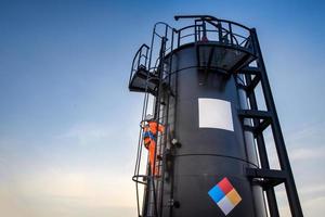 man working in Oil field site, climb oil tank for working photo