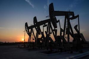 Oil field site, in the evening, oil pumps are running, The oil pump and the beautiful sunset of pumping unit in the evening. photo