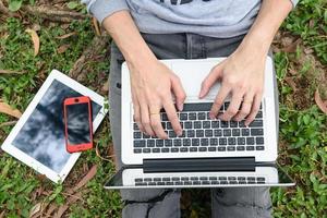 young man with phone and llaptop outdoors photo