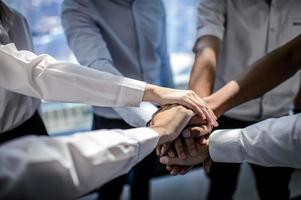 cerca de jóvenes empresarios juntaron sus manos. pila de manos concepto de unidad y trabajo en equipo. foto