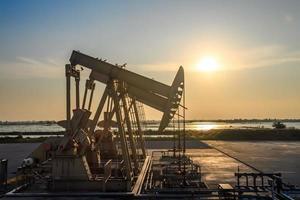 Oil rig or oil field In the evening, the gas station is running. Gas station and beautiful sunset of the pumping unit in the evening. photo