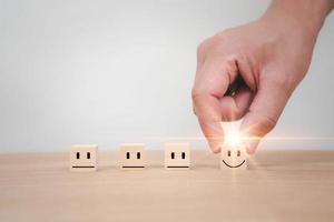 Hand chooses smile face on wood block cube photo