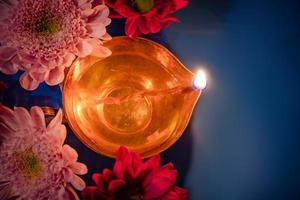 Celebrating Indian festival of light Diwali. Close-up of traditional diya oil lamps and flowers on blue background. photo