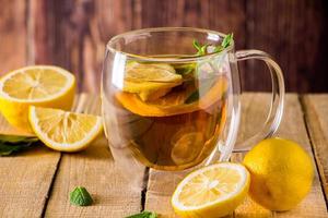Herbal tea with lemon and mint on wooden background. Delicious drink for relaxation and alternative therapy of diseases. photo