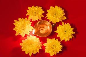 Diwali Indian Light Festival. Diya oil lamp and yellow flowers on red background. Traditional Hindu celebration. photo