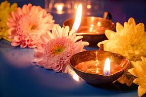 Happy Diwali. Burning diya oil lamps and flowers on blue background. Traditional Indian festival of light. photo