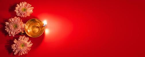 Happy Diwali. Diya oil lamp and flowers on red background. Traditional Hindu celebration. Religious holiday of light. photo