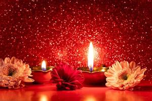 Happy Diwali. Burning diya oil lamps and flowers on red glittering background. Celebrating the traditional Indian festival of light. photo
