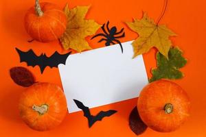 concepto de Halloween. decoraciones festivas. calabazas y tarjeta de felicitación sobre fondo naranja. foto