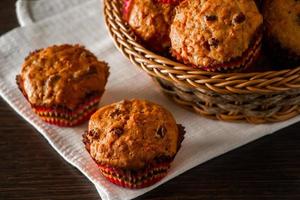 Muffins with raisins on a wooden background. Cupcake in a paper mold on a white napkin. photo