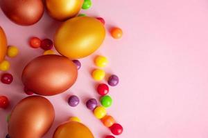 Happy Easter. Gold eggs and candies on a pink background. photo