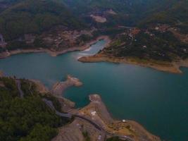 Turquoise water in a mountain forest lake with pine trees. Aerial view of blue lake and green forests. View on the lake between mountain forest. Over crystal clear mountain lake water. Fresh water photo