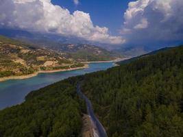 Turquoise water in a mountain forest lake with pine trees. Aerial view of blue lake and green forests. View on the lake between mountain forest. Over crystal clear mountain lake water. Fresh water photo