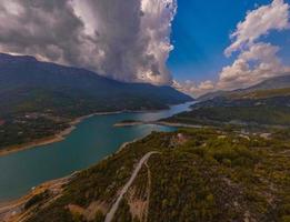 Turquoise water in a mountain forest lake with pine trees. Aerial view of blue lake and green forests. View on the lake between mountain forest. Over crystal clear mountain lake water. Fresh water photo