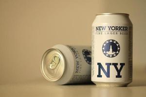 TERNOPIL, UKRAINE - JULY 18, 2022 Two cans of New Yorker fine lager beer with original logo and design on brown retro background photo
