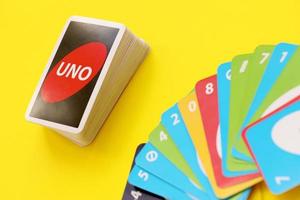 TERNOPIL, UKRAINE - MAY 15, 2022 Many colorful UNO game cards on yellow background. UNO is an American shedding-type card game that is played with a specially printed deck photo