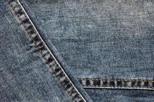 Detailed abstract texture of dark blue denim cloth. Background image of old used denim trousers fabric photo