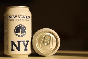 TERNOPIL, UKRAINE - JULY 18, 2022 Two cans of New Yorker fine lager beer with original logo and design on brown retro background photo