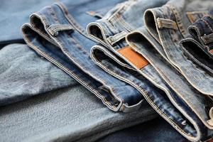 Many jeans in stack in wardrobe room. Row of pants denim jeans in closet. Concept of buy, sell, shopping and fashionable clothes photo