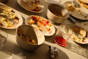 platos sucios vacíos con cucharas y tenedores en la mesa después de la comida. concepto de final de banquete. platos sin lavar foto