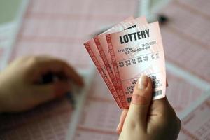 llenando un boleto de lotería. una mujer joven sostiene el billete de lotería con una fila completa de números en el fondo de las hojas en blanco de la lotería. foto