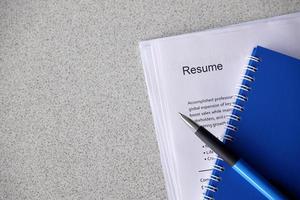 Top view of stack of office documents including resume and cv forms on the desk close to pen and notepad. Job seeking process. Hunting for workplace photo