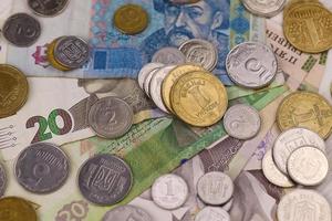 billetes y monedas de dinero ucraniano de cerca. gran cantidad de billetes de hryvnia y monedas pequeñas en la mesa. negocios e inversiones foto