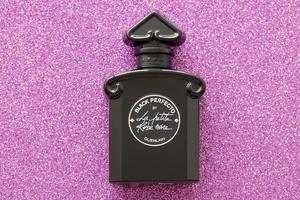 TERNOPIL, UKRAINE - SEPTEMBER 2, 2022 Black Perfecto La Petite Robe Noire by Guerlain perfume bottle on shiny glitter background in pink colors photo