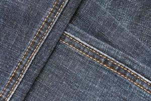 Detailed abstract texture of dark blue denim cloth. Background image of old used denim trousers fabric photo