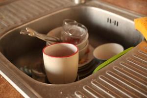 Stack of dirty dishes with food leftovers in the kitchen sink. Unwashed dishes photo