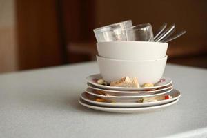 Stack of dirty dishes with food leftovers on the table after meal. Banquet ending concept. Unwashed dishes photo