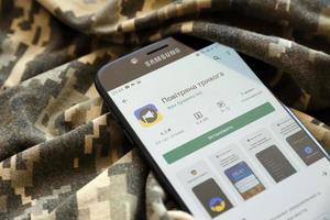 TERNOPIL, UKRAINE - APRIL 24, 2022 Air Raid Siren app for mobile phone on smartphone display screen on the military camouflage photo