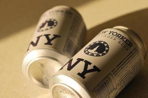 TERNOPIL, UKRAINE - JULY 18, 2022 Two cans of New Yorker fine lager beer with original logo and design on brown retro background photo
