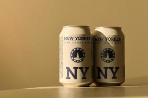 TERNOPIL, UKRAINE - JULY 18, 2022 Two cans of New Yorker fine lager beer with original logo and design on brown retro background photo