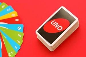 TERNOPIL, UKRAINE - MAY 15, 2022 Many colorful UNO game cards on red background. UNO is an American shedding-type card game that is played with a specially printed deck photo