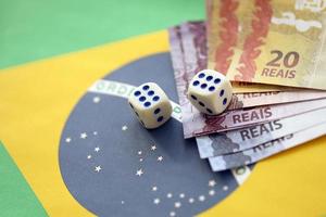 cubos de dados con billetes de dinero brasileño en la bandera de la república de brasil. concepto de suerte y juego en brasil foto