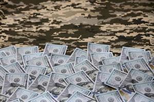 billetes de dólares estadounidenses en tela con textura de camuflaje pixelado militar ucraniano. tela con patrón de camuflaje en formas de píxeles grises, marrones y verdes foto