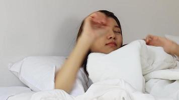 linda mulher asiática acorda de manhã por um despertador. video
