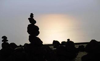 Stacked pebbles on Mount Vesuvius during sunset with the ocean in the background photo