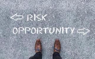 Top view on a man standing in front of the words Risk and Opportunity with arrows pointing to the left and right side of the picture photo