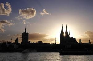 el sol se pone en medio de las torres de la catedral de colonia foto