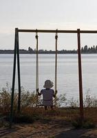 niña en un columpio frente al lago issyk kul en Kirguistán foto