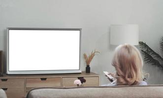 detrás de una joven asiática viendo televisión de pantalla blanca en el sofá de casa foto
