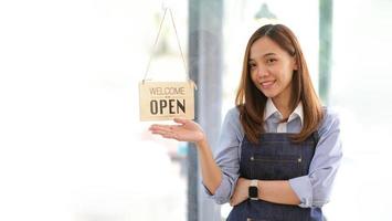 Startup successful small business owner sme beauty girl stand with tablet smartphone in coffee shop restaurant. Portrait of asian tan woman barista cafe owner. SME entrepreneur seller business concept photo