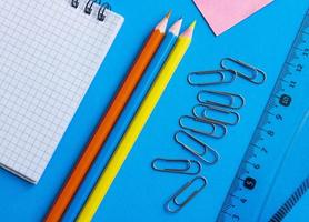 school stationery on a blue background. Geometric set, ruler, pencils, notepad, paper clips. the concept of education. photo