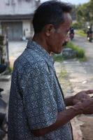 un hombre de mediana edad parado mientras juega en las redes sociales en un smartphone.magelang, indonesia 15. 09 2022. foto