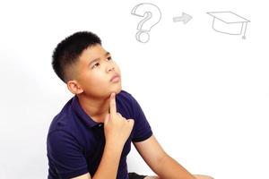 Thinking boy on white background with graduation cap. Bright ideas and problem solving concept. photo
