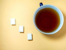 Pieces of sugar a cup of tea on a beige background. Sweet product. photo