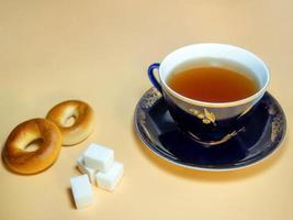 A cup of black tea with sugar cubes and sushki. photo